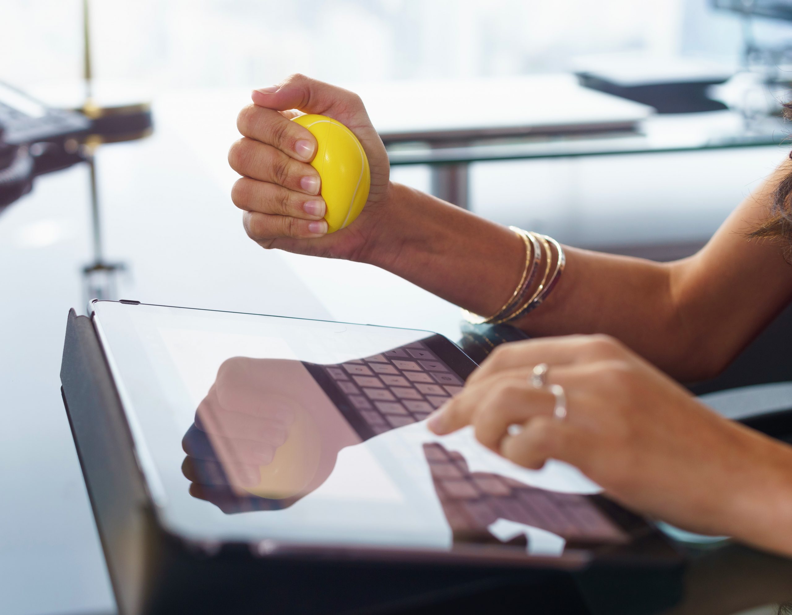 Stressed office worker with anti stress ball types email